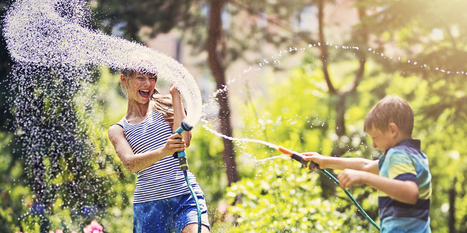 Gartenwasserzähler: Kinder spielen im Garten mit einem Wasserschlauch